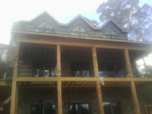 Dormers and porch framing on a large log home under construction — Roof Coating work by our crew in Webster